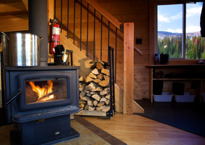 A wood-fired stove in the living room of the Mallard Mountain Lodge with outside views.