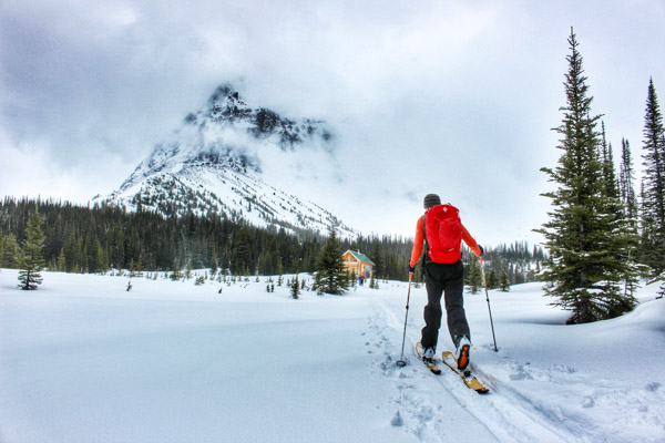 Man ski touring through a meadow towards the Mallard Mountain Lodge