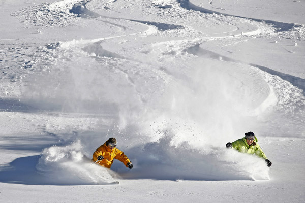 Two men skiing powder next to each other