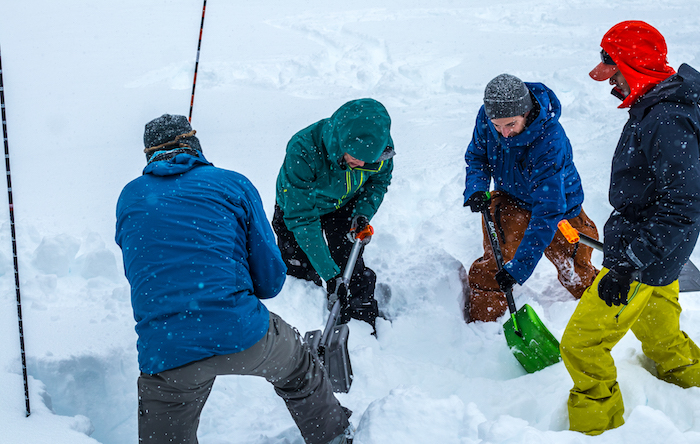 Group practicing digging out a buried person with their avalanche shovels 