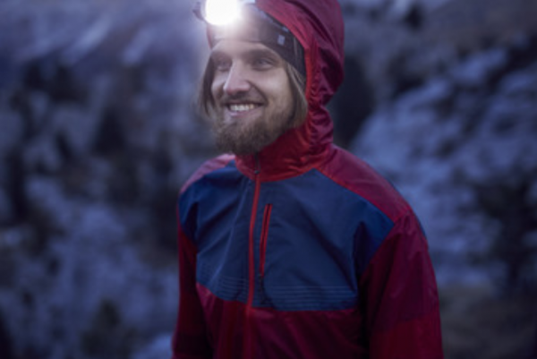 Man smiling at dusk wearing a headlamp