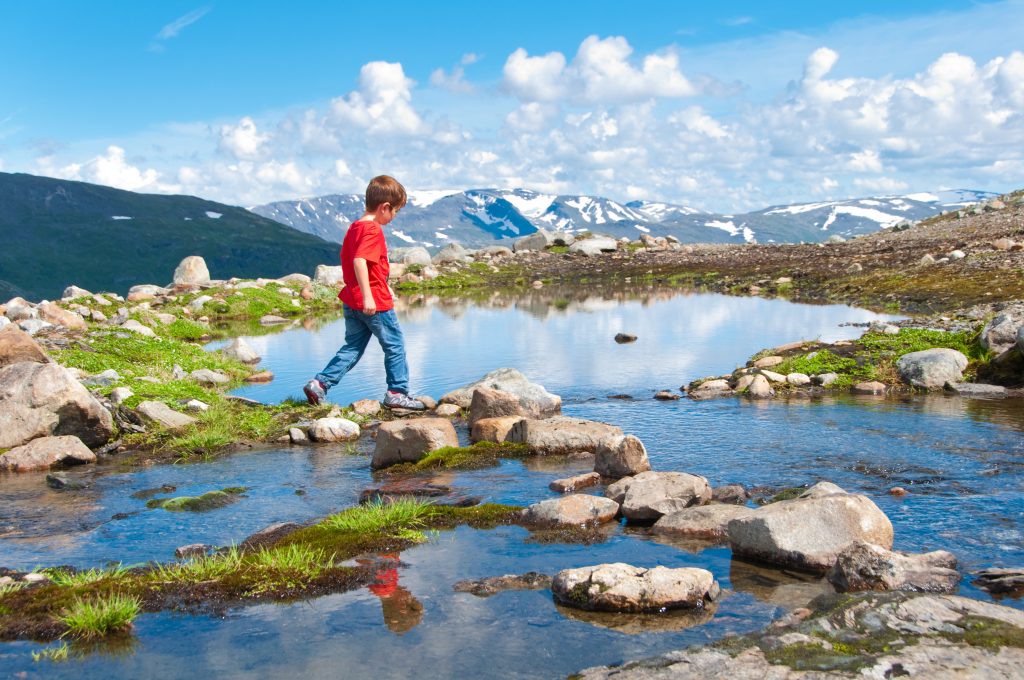 Child crossing mountain lake