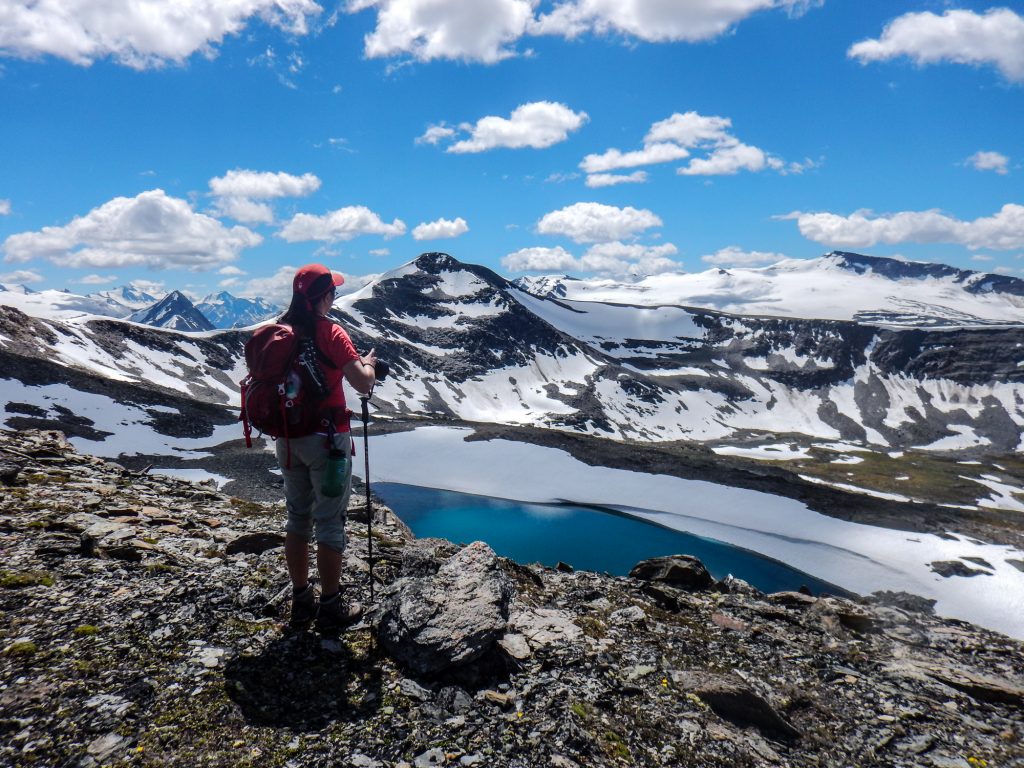 Hiker stood at the edge of a glacier lake in the Rocky Mountains