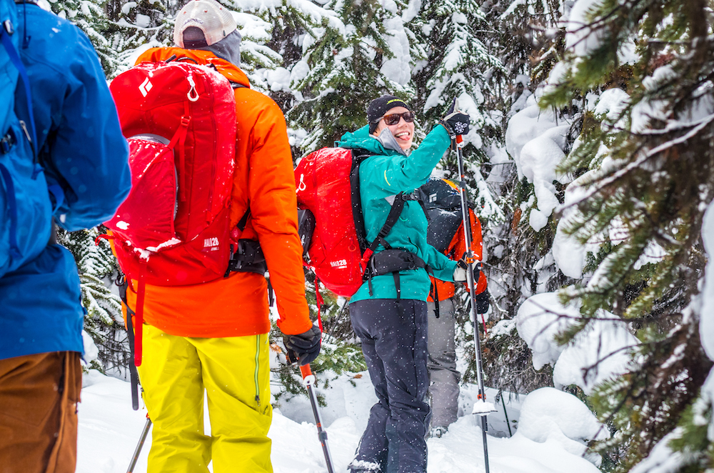 Woman giving thumbs up an smiling in a group of backcountry skiiers