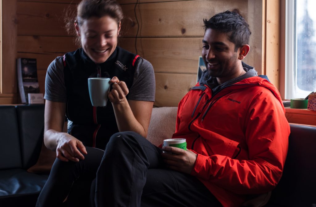 Couple smiling and enjoying coffee at a backcountry ski lodge in BC