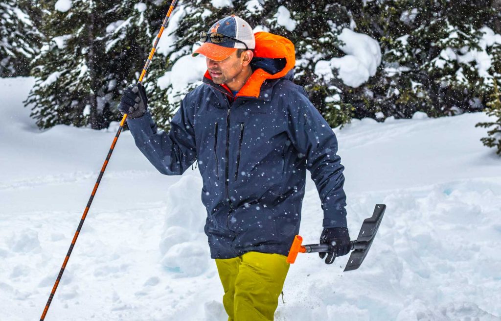 Man carrying avalanche shovel and probe