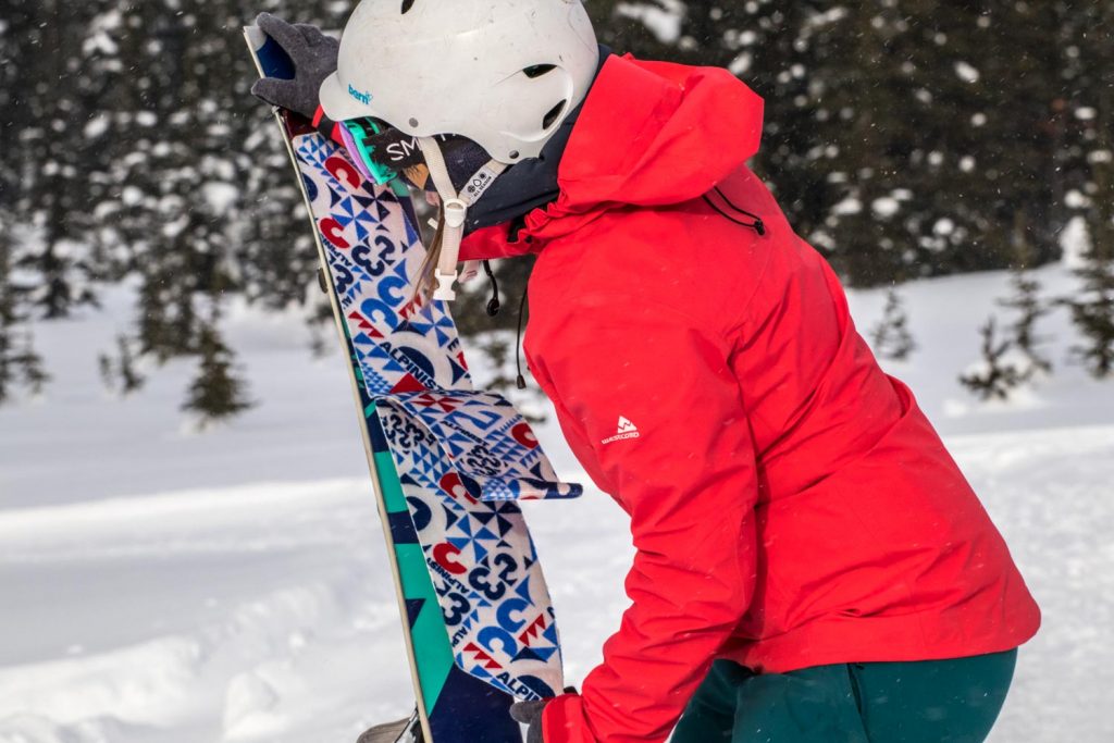 woman in ski gear attaching a skins to the bottom of her skis