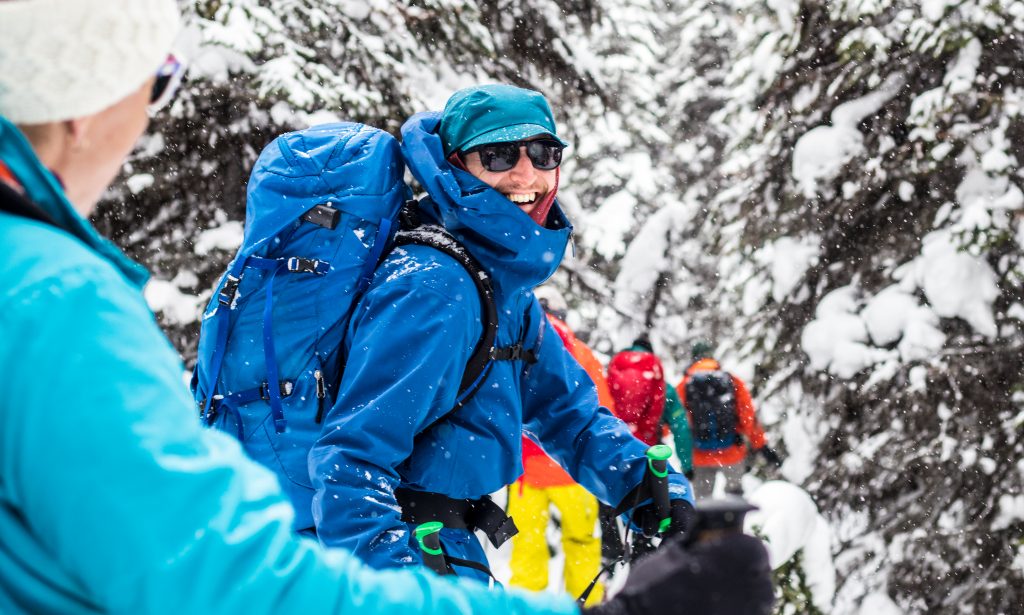 ski touring man stood in forest smiling at the camera