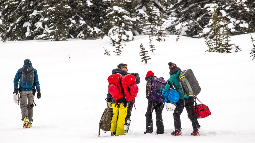 Group of people unloading from a helicopter drop off in the canadian backcountry