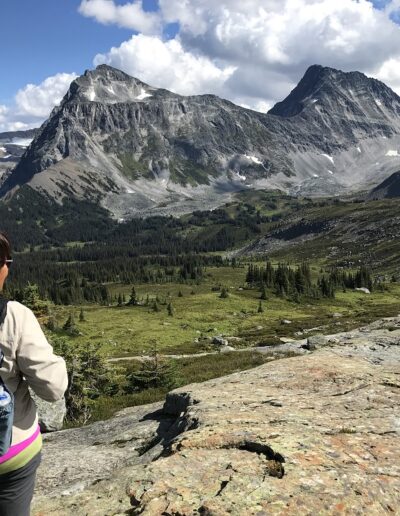 hiker on glaciated smooth rock viewing steep mountains