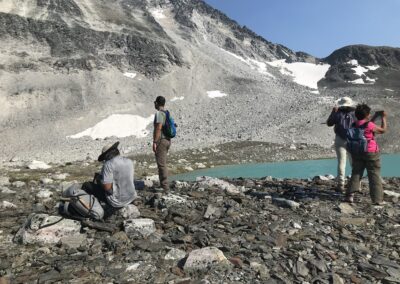 hikers at high alpine lake viewing steep mountains