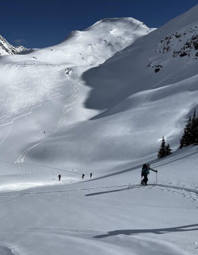 skiers climbing with runs in background